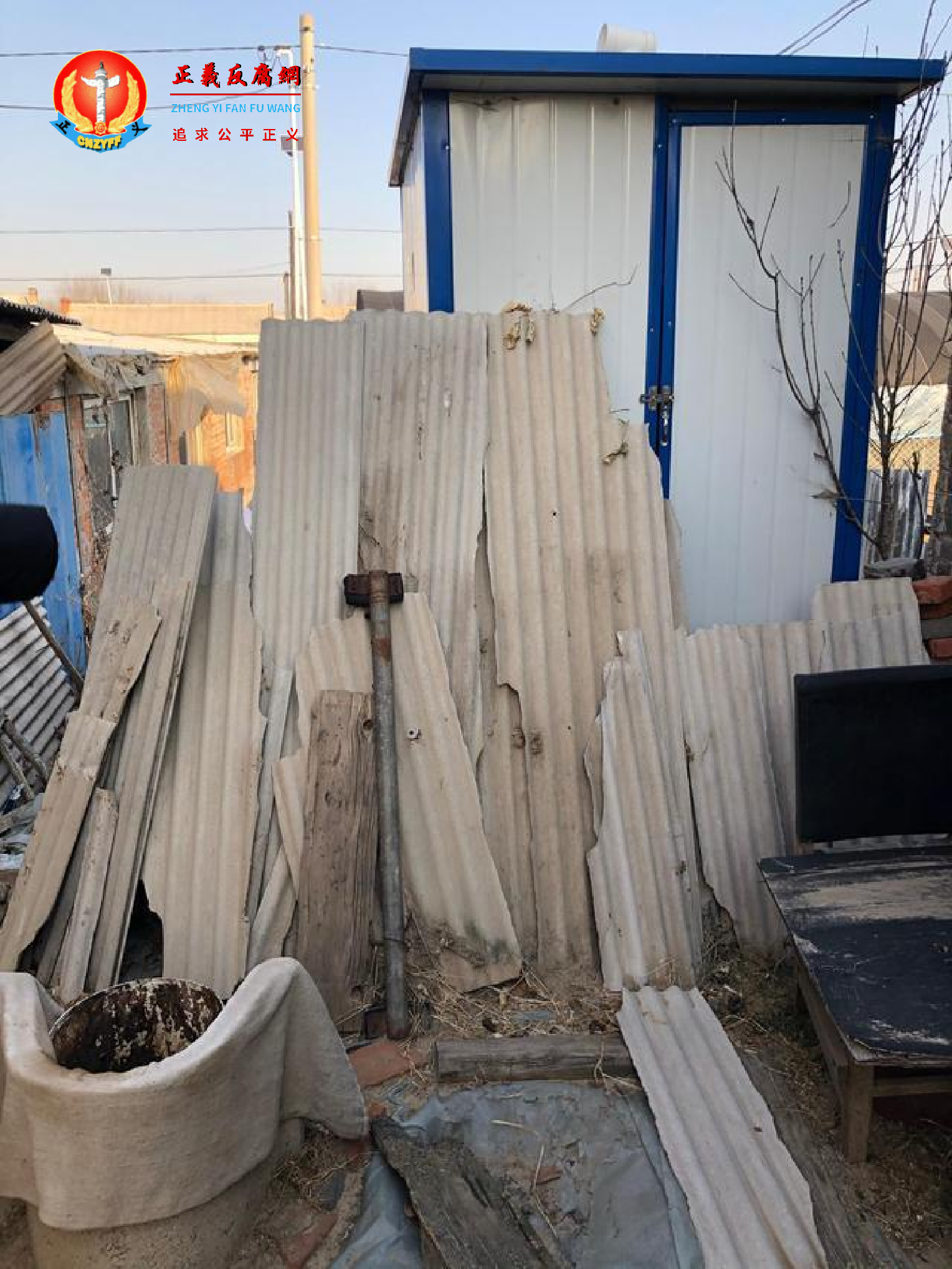 厕所前堆满了木板、秸秆等杂物，年逾八旬的村民用前面的铁桶“方便”。.png